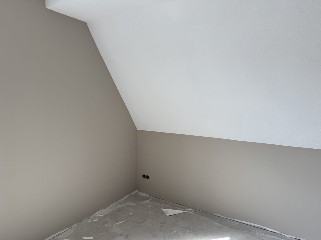 Zolderkamer in een nieuwbouwwoning met een schuine wand en strak afgewerkte lichte wanden